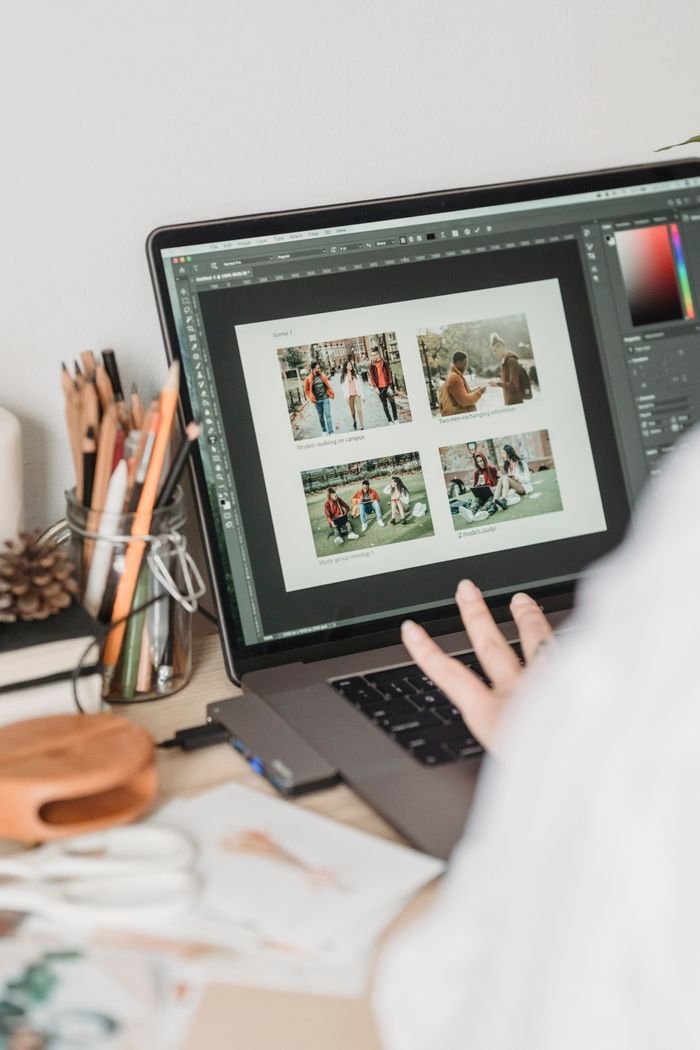 team-01 Crop unrecognizable female freelancer using touchpad while retouching photos on laptop during remote work at home